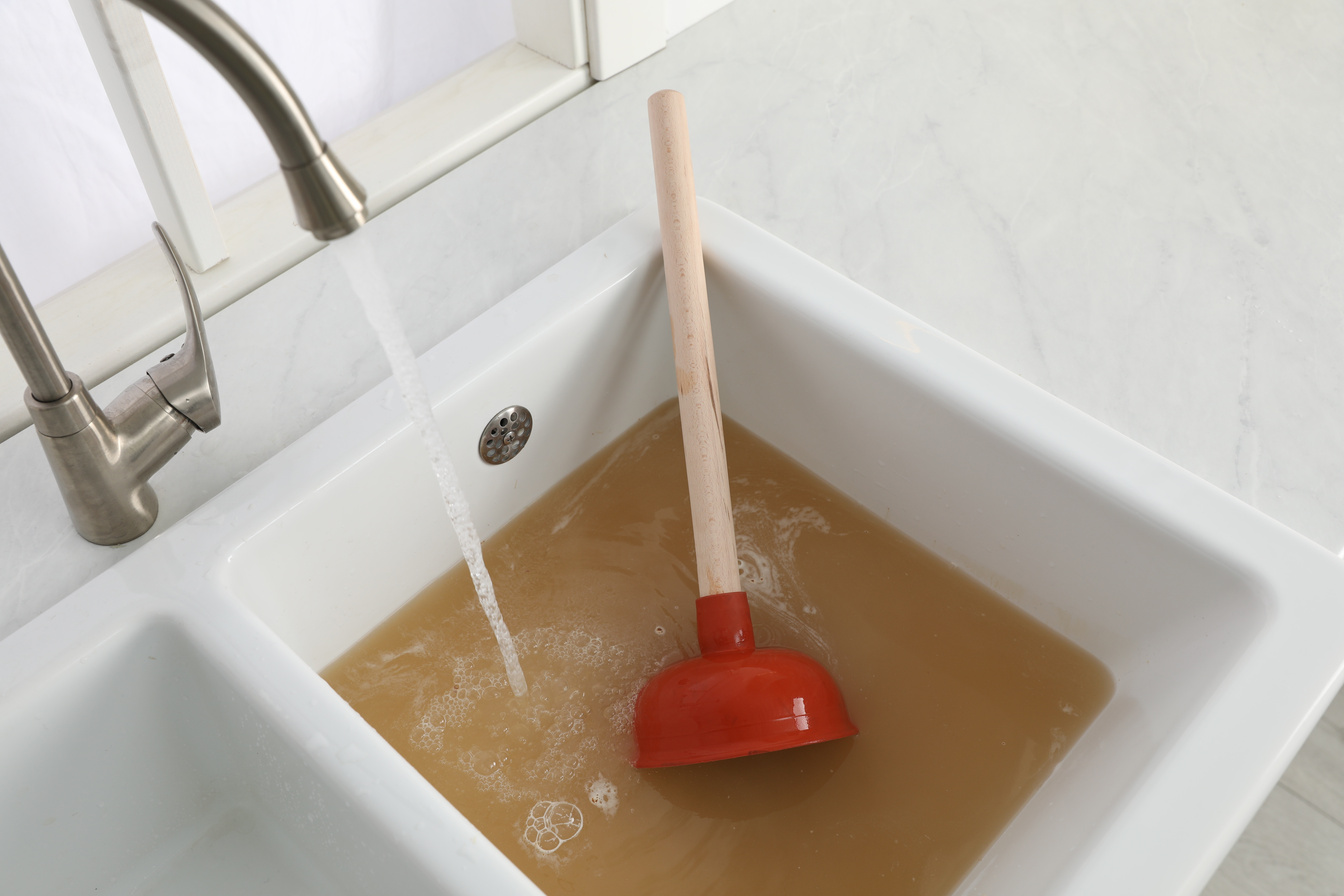 Clogged Kitchen Sink with Plunger and  Water